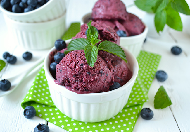 Scoops of blueberry ice cream in white bowl